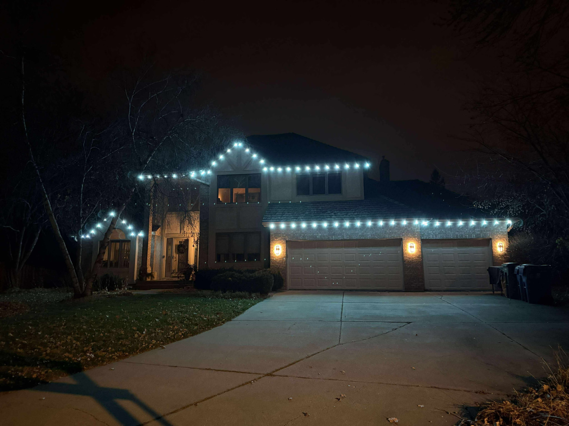 Cool white roofline lighting across a two-story home